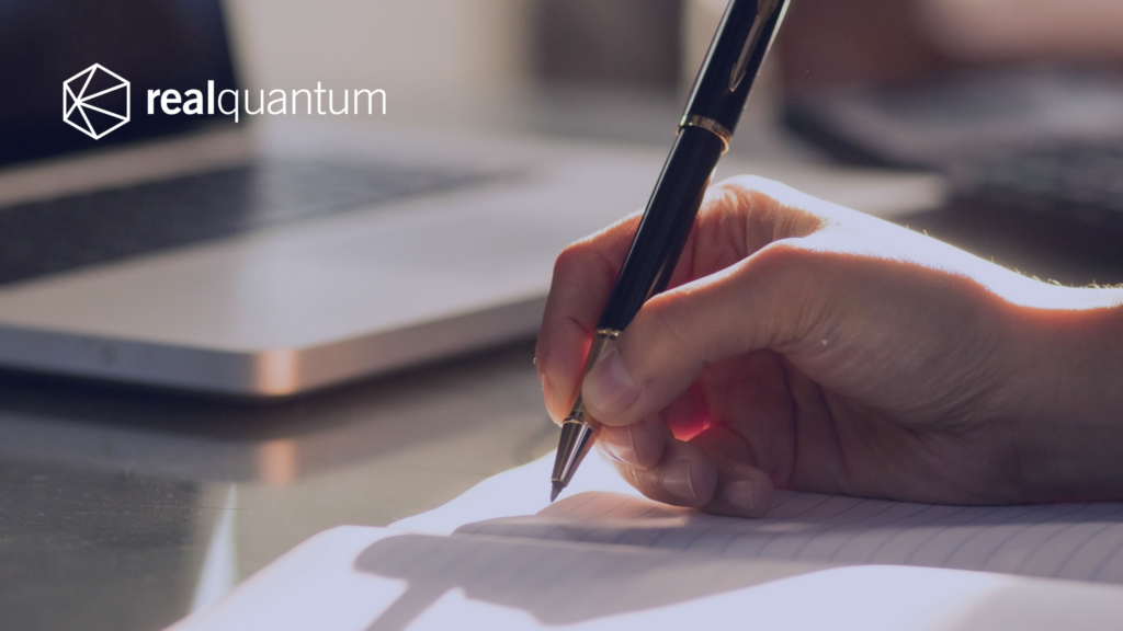 Employee writing calculations with a computer in the background.